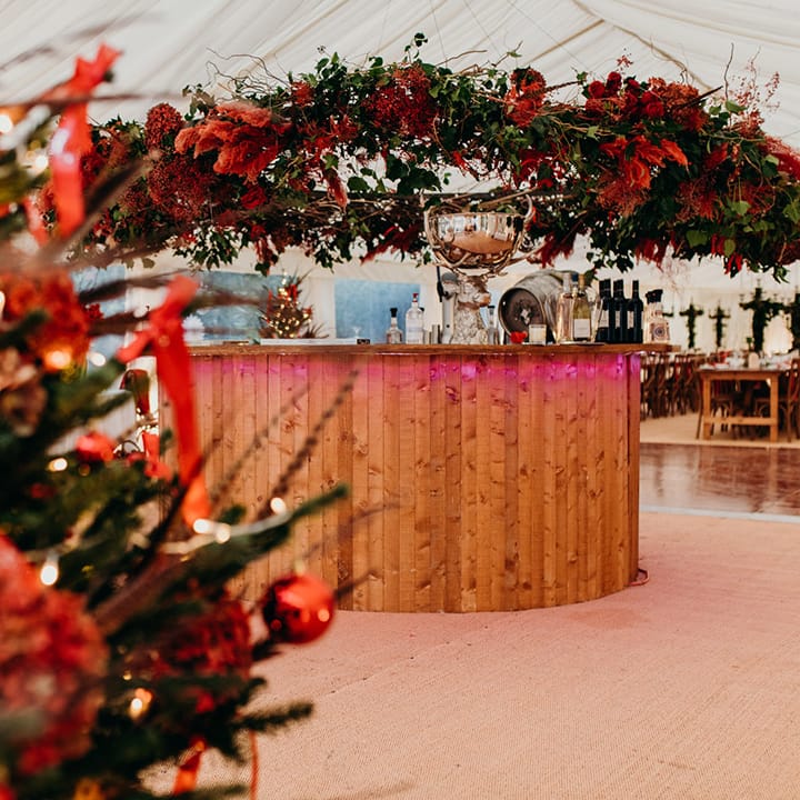 Christmas themed wedding reception room with large winter foliage decorations and arches, red flowers, acorns and fairy lights