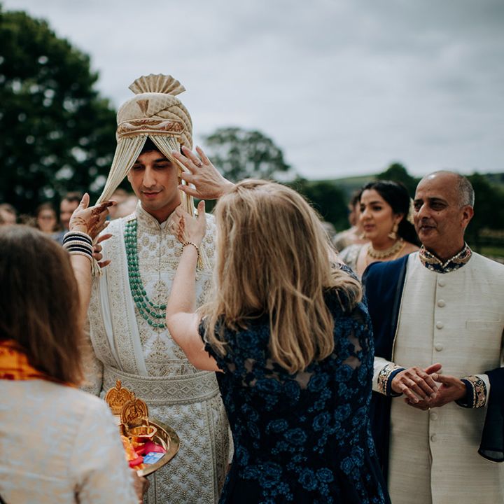 Grooms face is covered with beads outdoors during Haldi ceremony for multicultural wedding