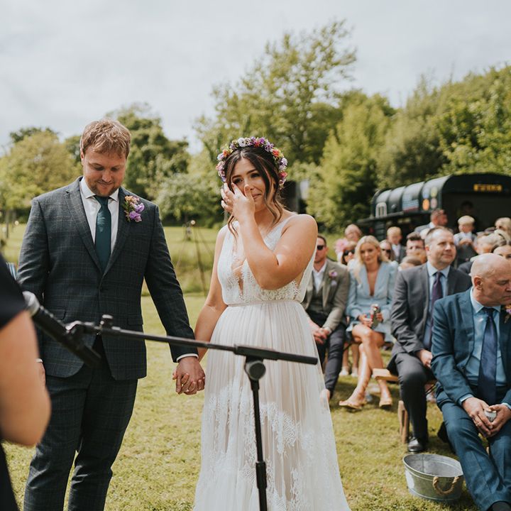 Bride wears boho styled scallop lace wedding dress with colourful floral crown