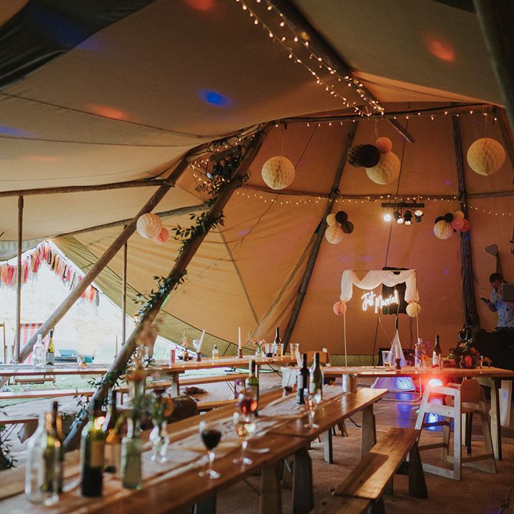 DIY tent wedding complete with neon signage, colourful bunting and wooden banquet tables 