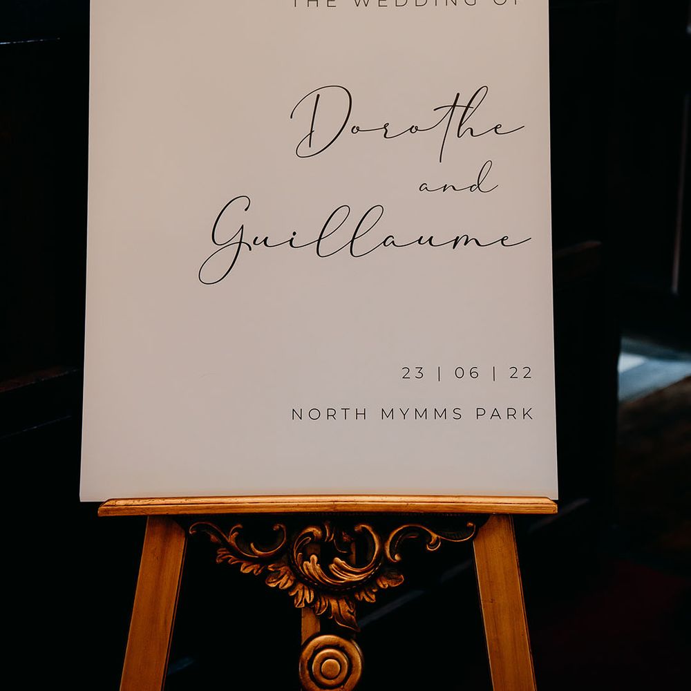 Plain black and white wedding welcome sign on a decorative gold easel