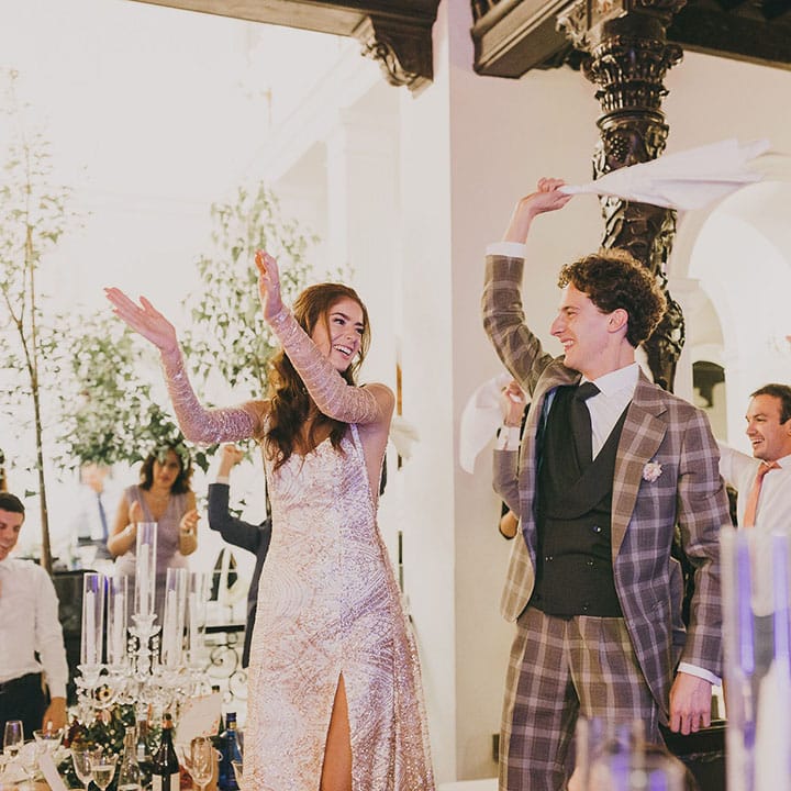 wedding reception with bride in a sparkly wedding dress with front slit and groom in a three piece check suit 