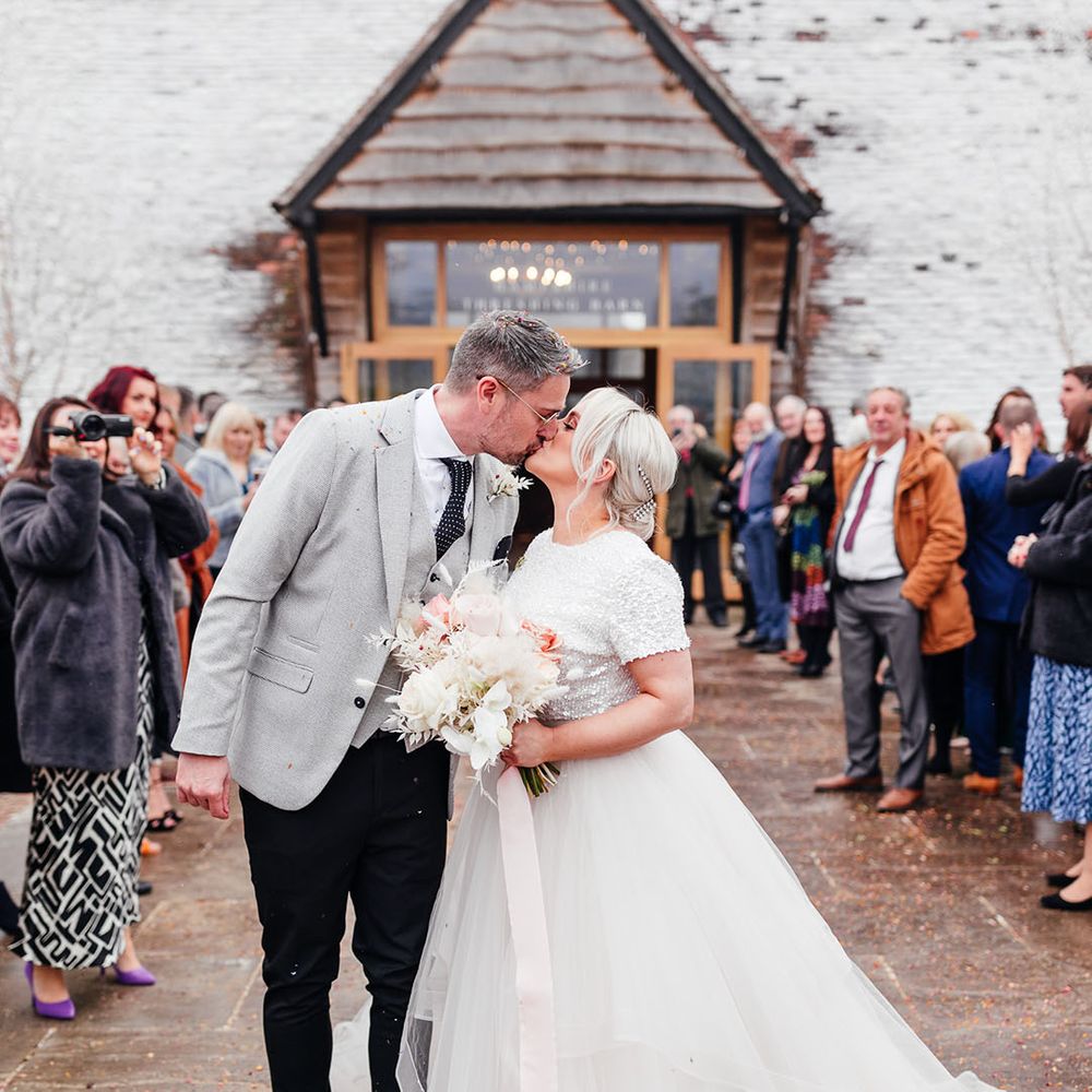 Bride wearing short sleeve beaded top and tulle bridal skirt kissing the groom after their wedding ceremony 