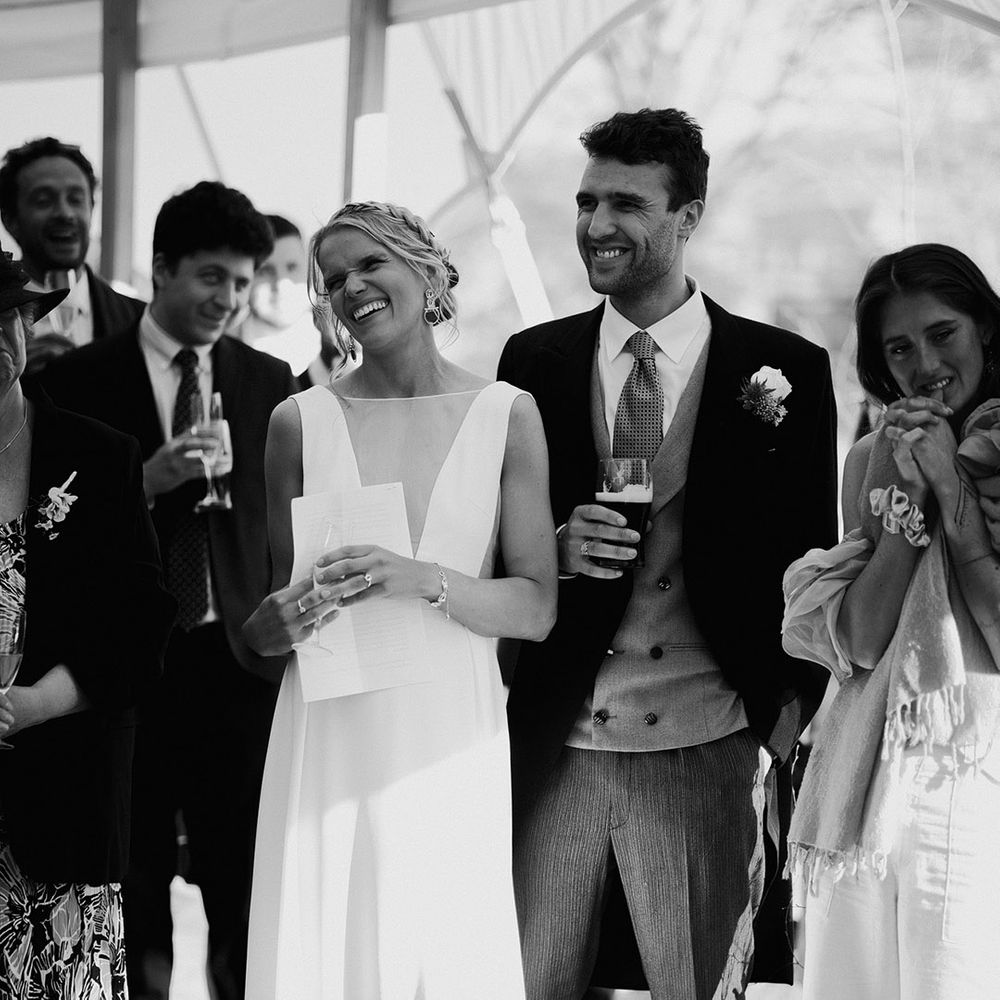 The bride and groom smile happily as they listen to the wedding speeches 