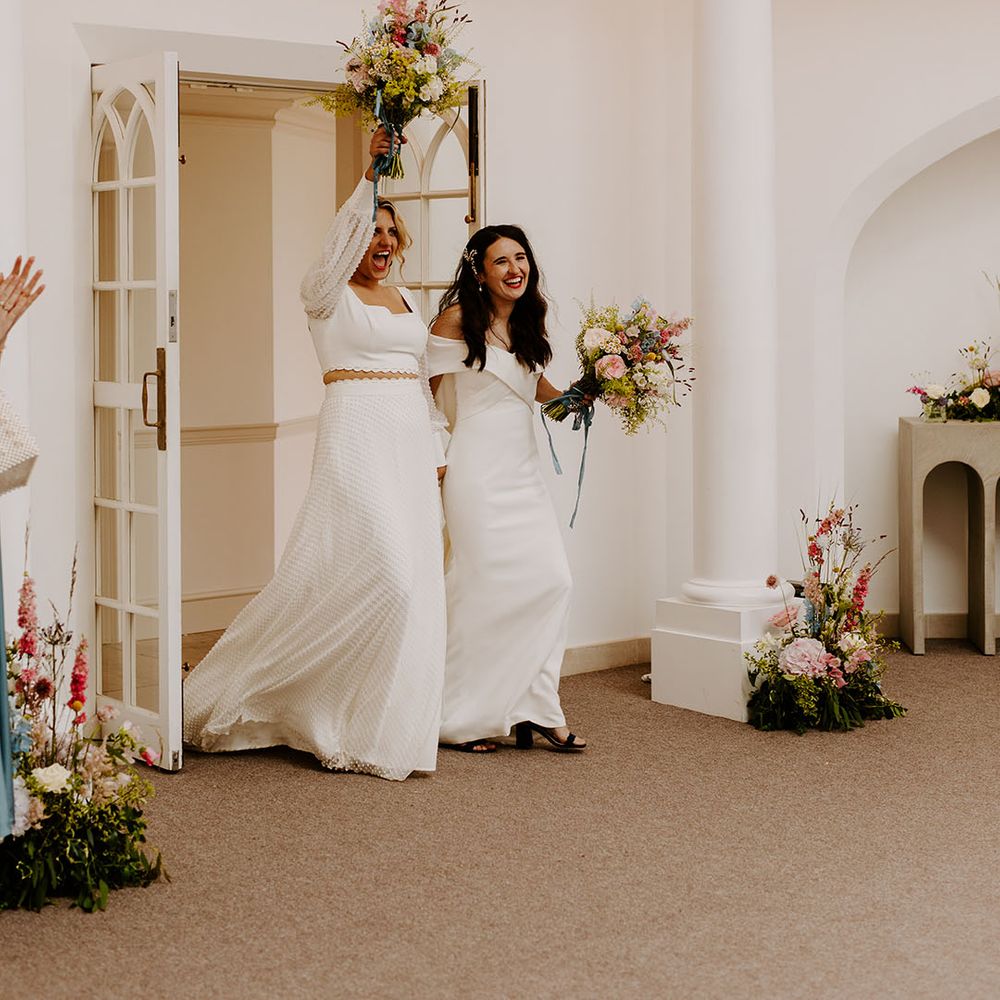 Two brides celebrate as they enter their wedding reception together at Pennsylvania Castle Estate venue 