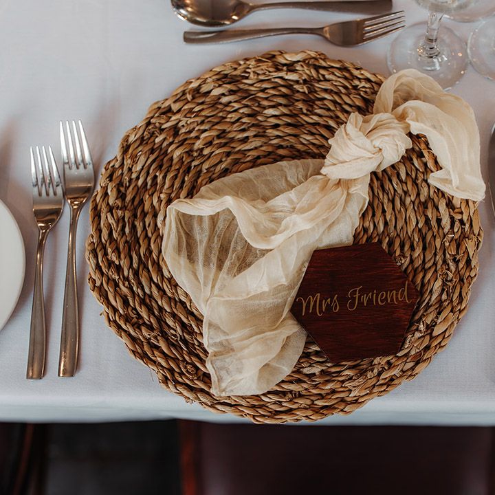 Wicker place mat with sheer white wedding napkin and burgundy wedding place name table setting 