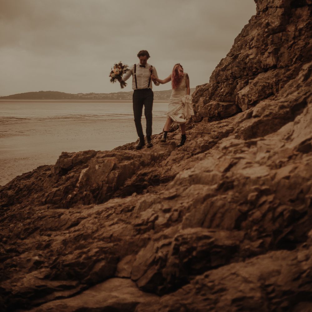 Bride and groom walking on the rocks at beachside elopement