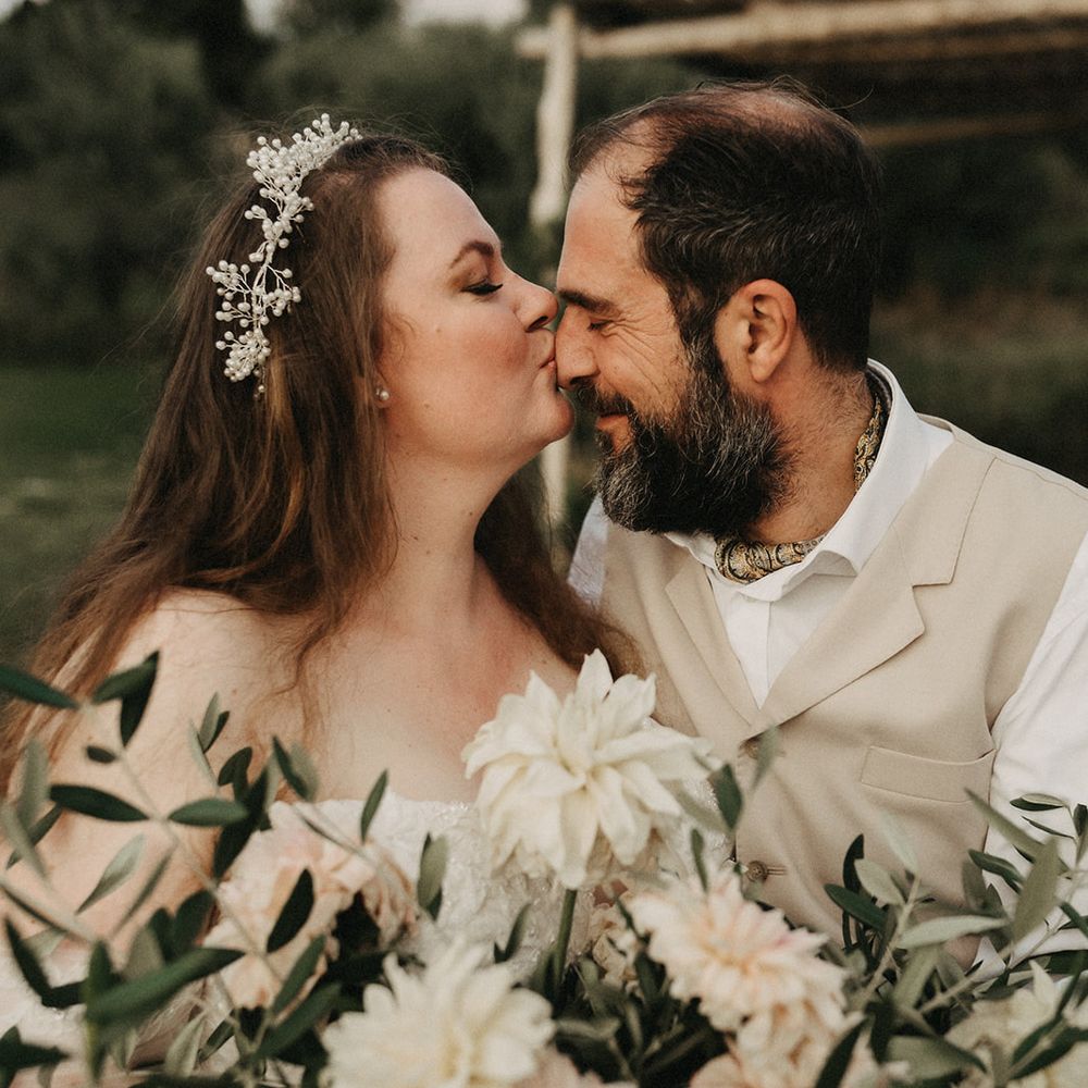 Bride kisses Groom's forehead with olive bouquet