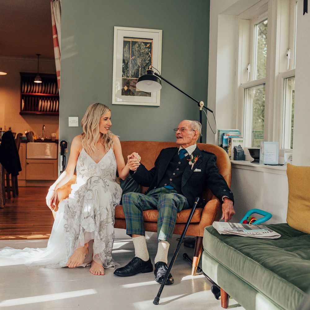 Bride sits with wedding guest who is wearing Tartan trousers