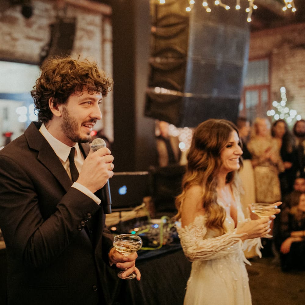 The groom and bride holding a glass of champagne and making speeches at Block 33