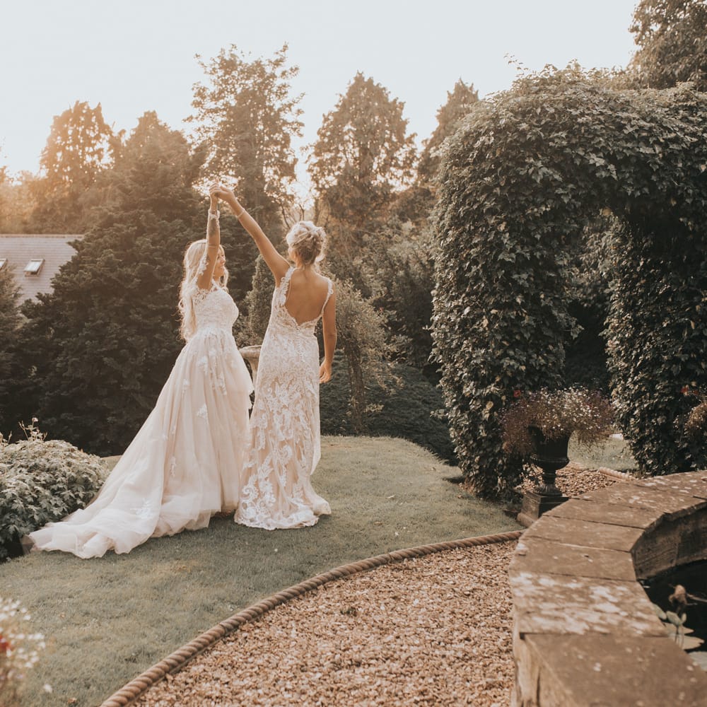 Two brides dance int he grounds of Crab & Lobster at sundown.