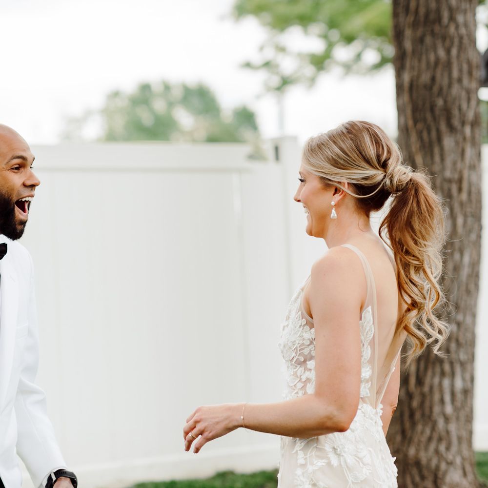 Surprised and happy grooms first look at bride in white Made With Love wedding dress at backyard wedding