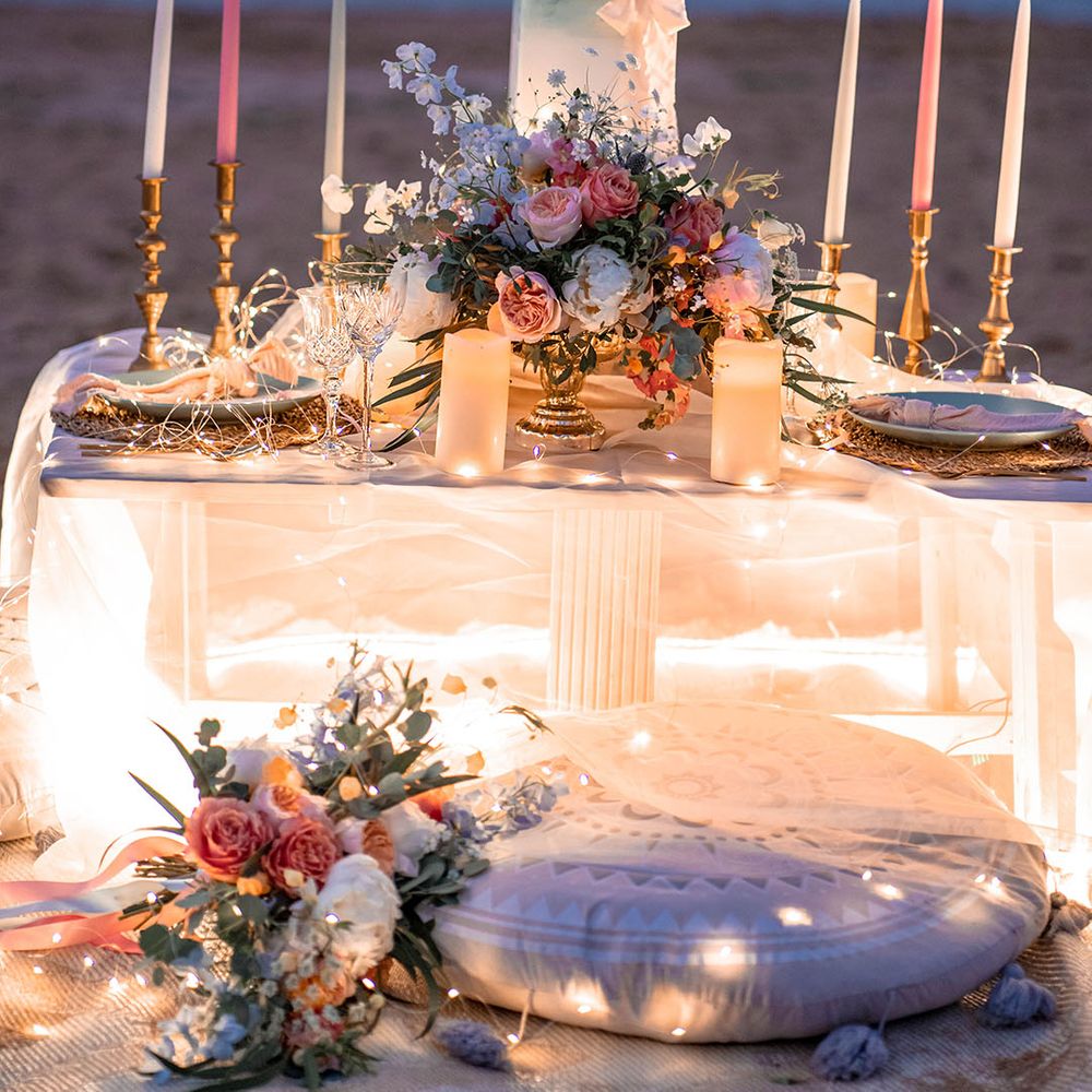 relaxed low table, cushions and fairy lights on the beach 