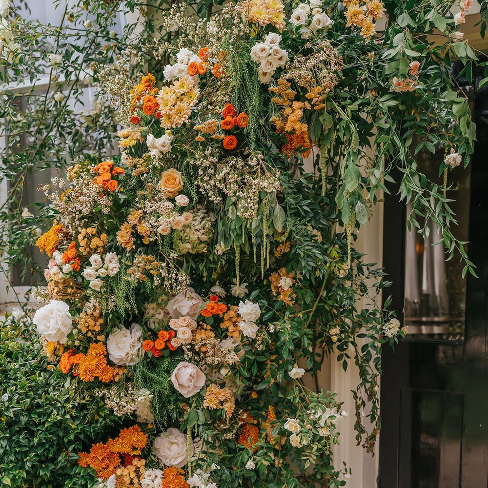 orange, peach and green wedding flower arrangement at the entrance to Modern Hall, London 