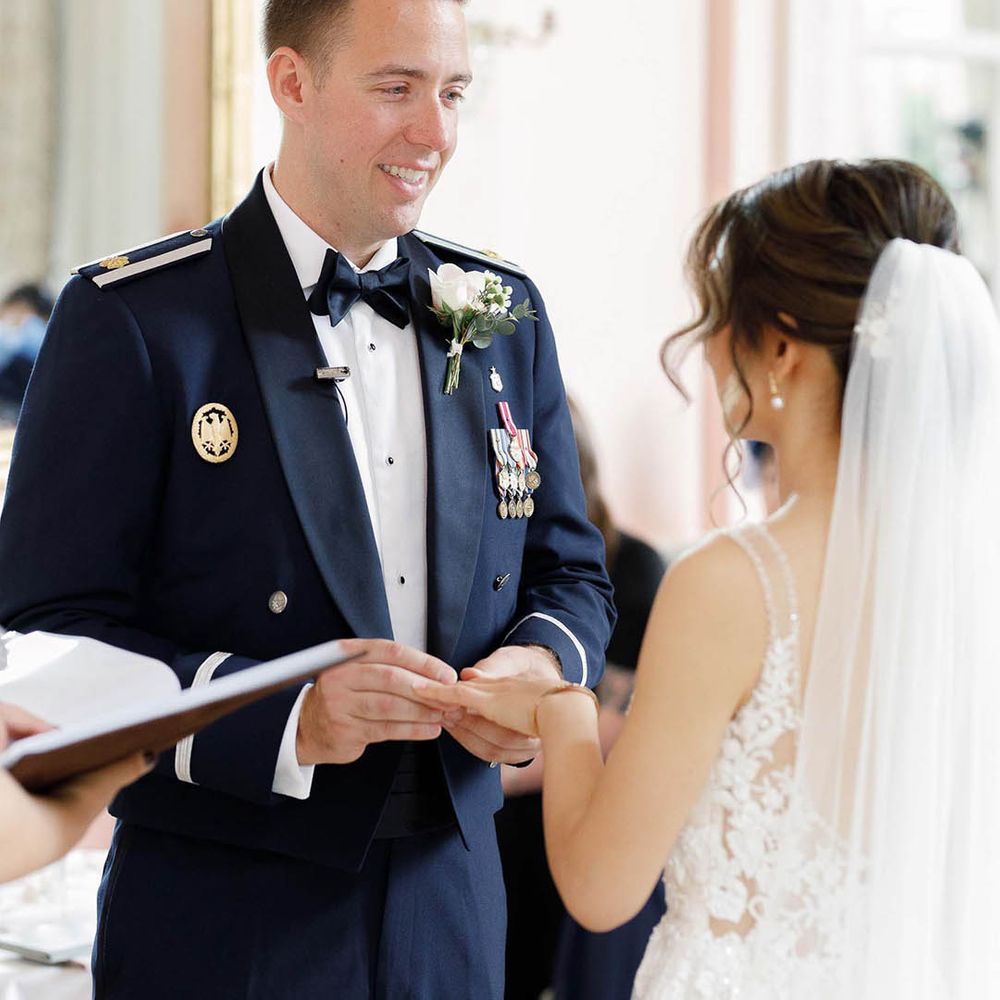 Groom wears Military Uniform and looks lovingly at his bride during wedding ceremony