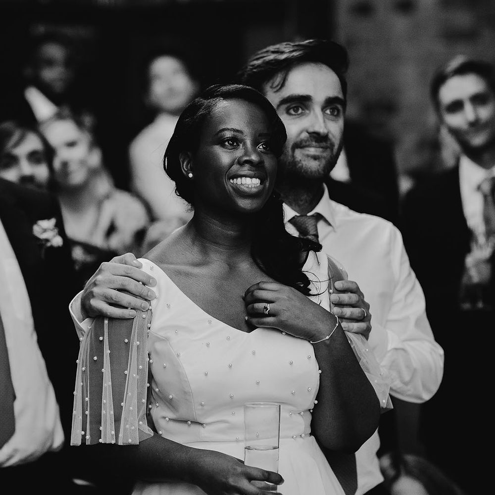 Black and white portrait of the groom holding his brides shoulders as they listen to the wedding speeches at their 100 Barrington wedding 