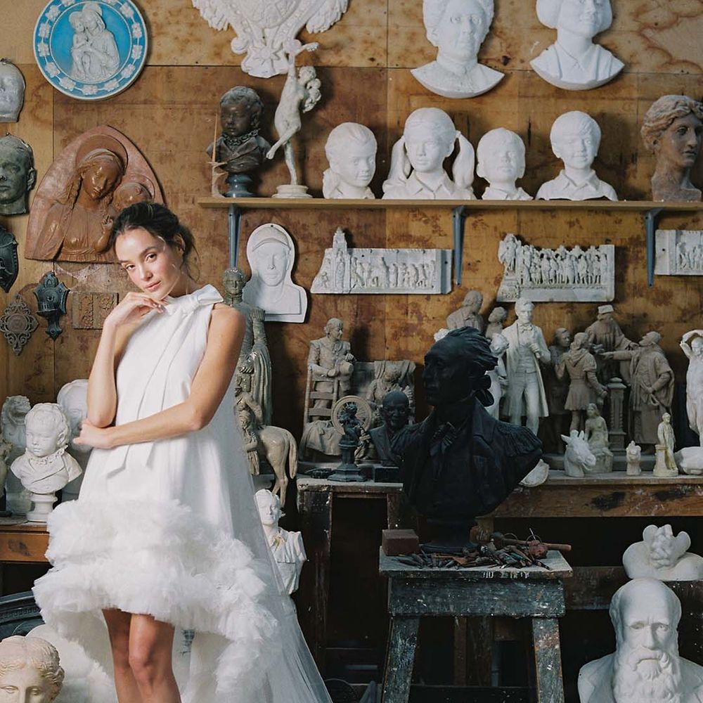 Bride in high low wedding dress with ruffles, train, and a bow and white wedding shoes with stiletto heel, ankle strap and white flower