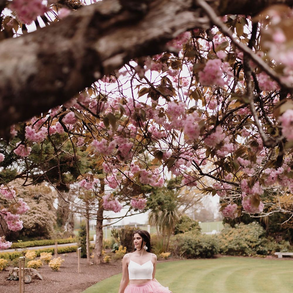 Bride in a pink ruffled wedding skirt with front slit and white top in Ballykealey House gardens 