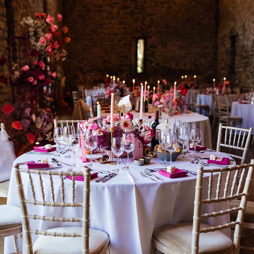 Eco candle wedding favours, bright pink fabric napkins and bright floral centrepiece for modern tablescape look