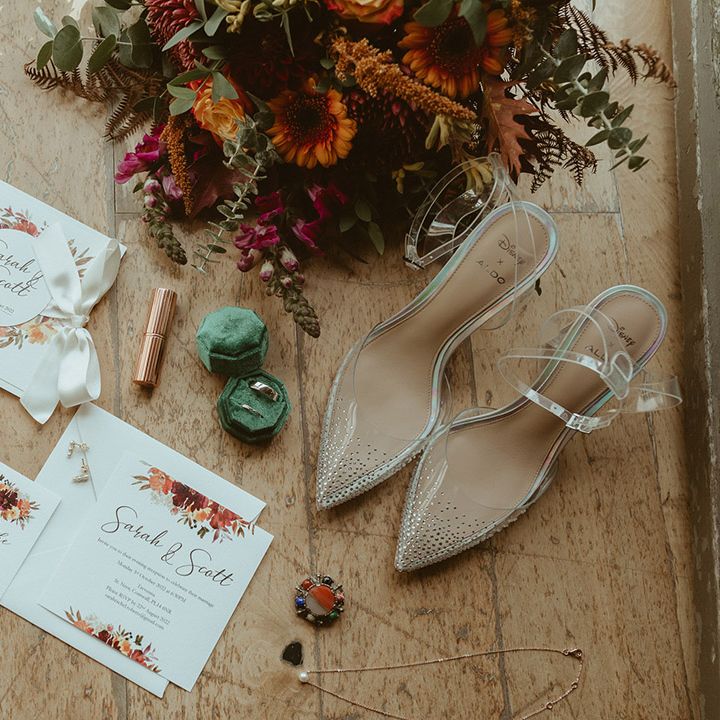 Autumn leaf theme wedding stationery with the bridal bouquet, Charlotte Tilbury lipstick, green velvet ring box and wedding bands with sparkly Cinderella wedding shoes