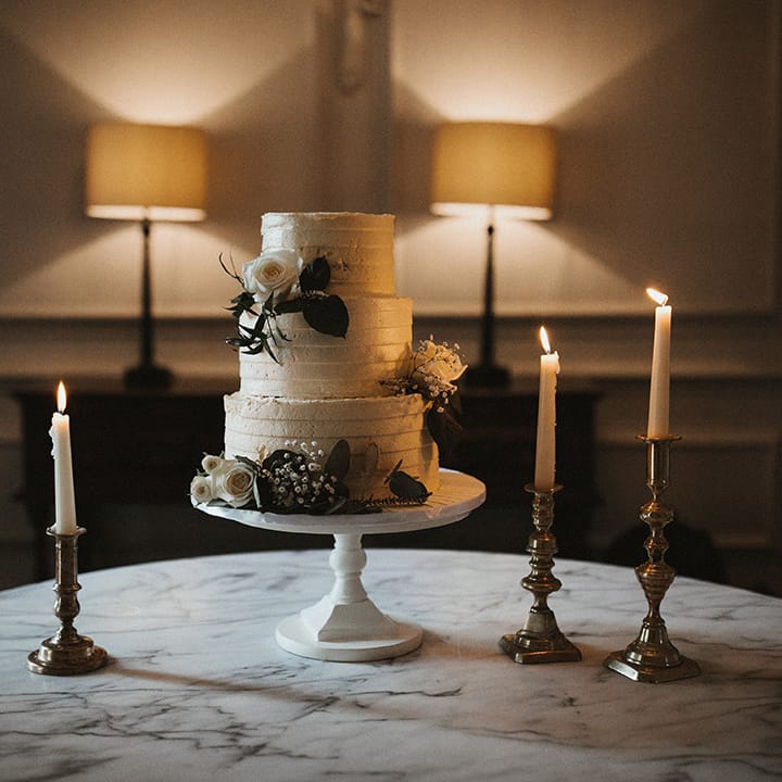Three tier white frosted rustic wedding cake with white roses and gypsophila 