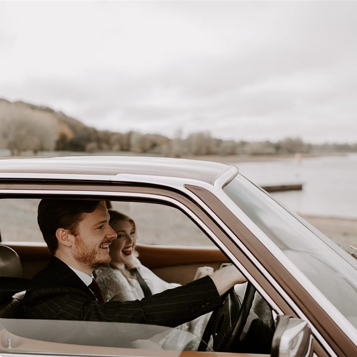 The groom drives the bride over to their wedding reception in brown Mercedes wedding car 