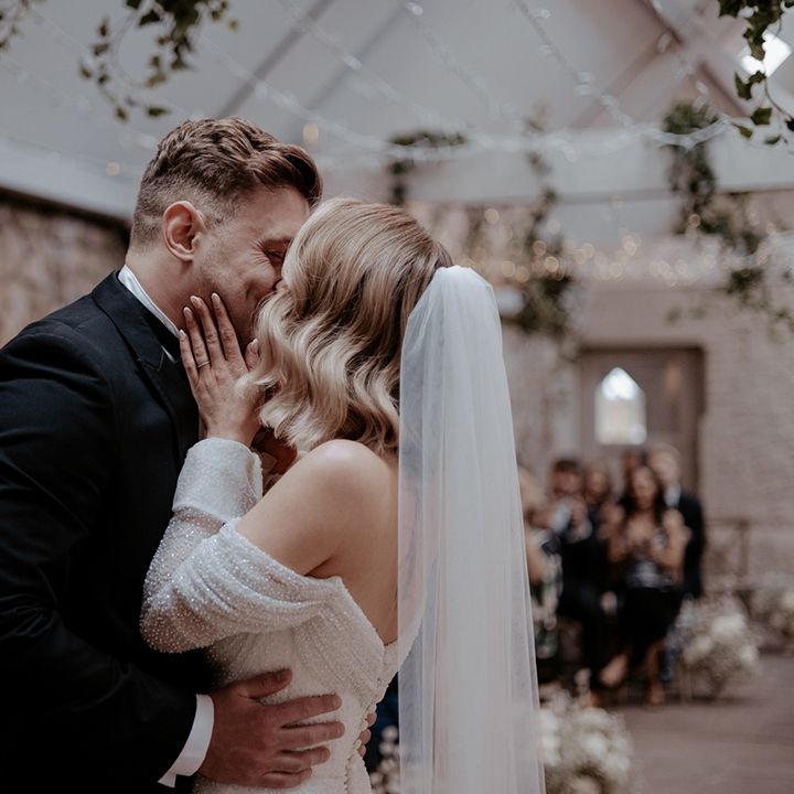 The bride and groom share their first kiss as a married couple for their luxe style wedding day 