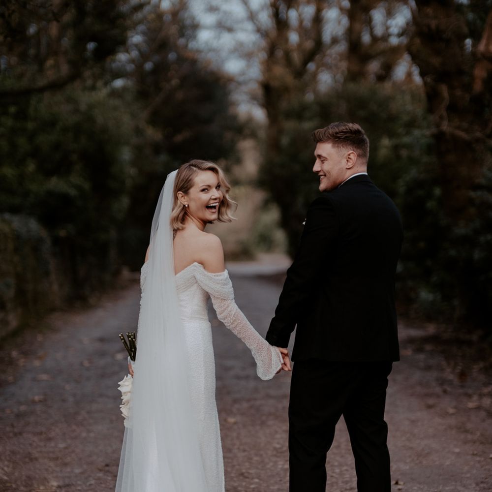 The bride and groom laugh together as they walk around the grounds of the Lancashire wedding venue together 