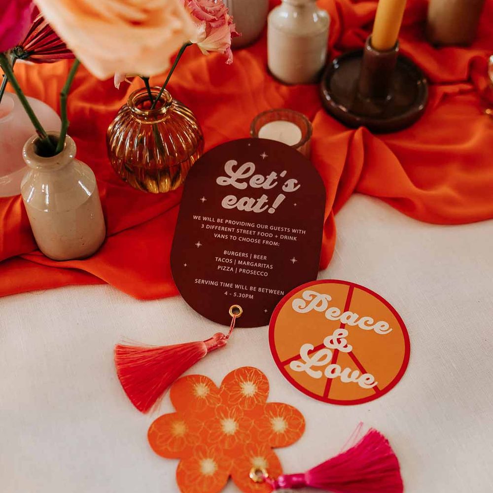 Retro wedding stationery at Northern Monk Refectory Leeds - orange and mauve retro wedding stationery with white bold lettering and tassels with disco ball decorations 
