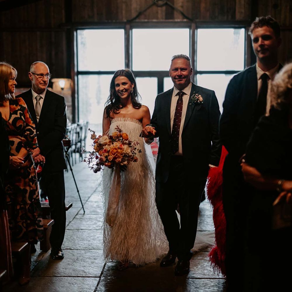 Bride in strapless ivory fringed crepe gown and chapel length veil walking down the aisle at Willow Marsh Farm Loughborough 