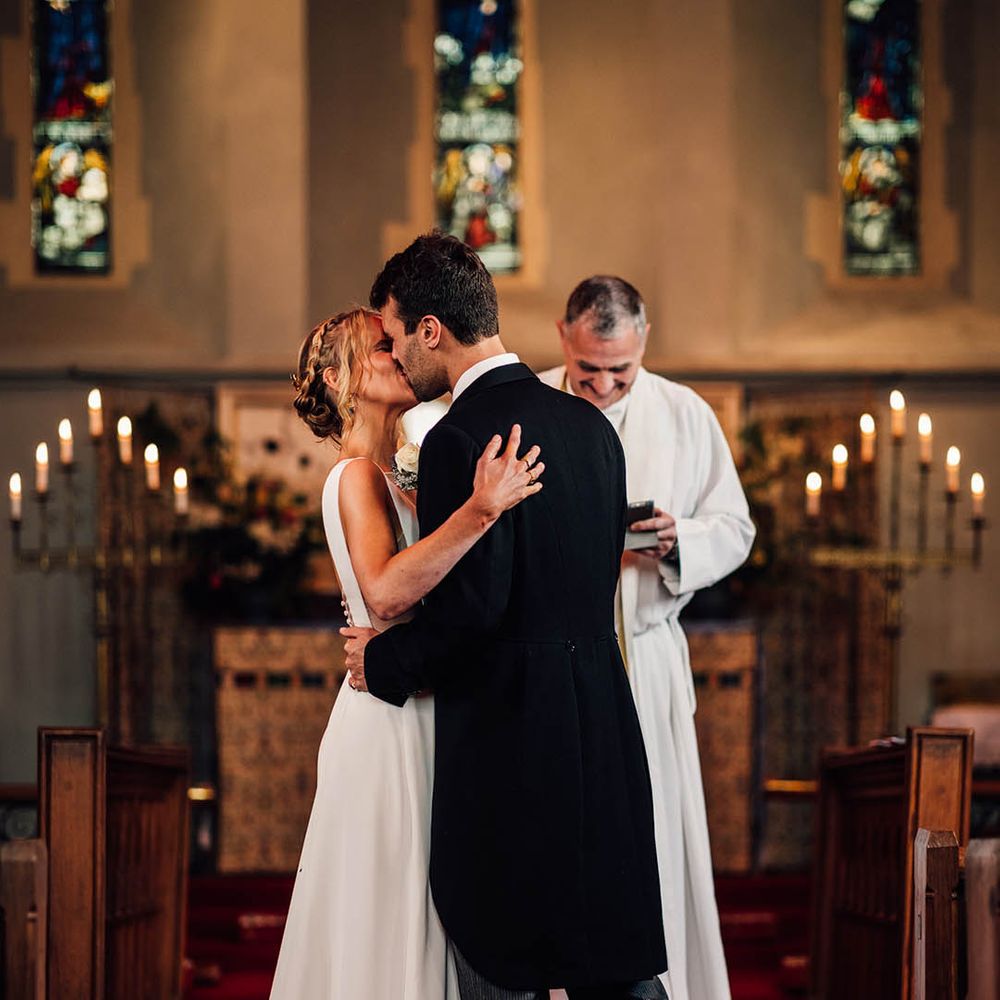 The bride and groom share their first kiss as a married couple at their wedding ceremony 