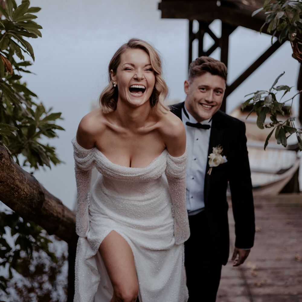 Bride wearing an off the shoulder wedding dress laughing with groom at their winter wedding 