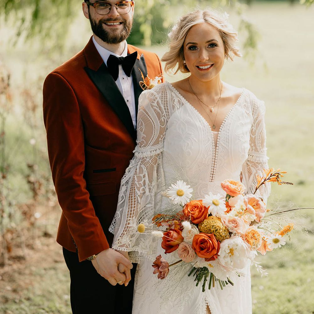 Bride in long bell sleeve wedding dress with groom in velvet suit jacket posing for couple portrait 
