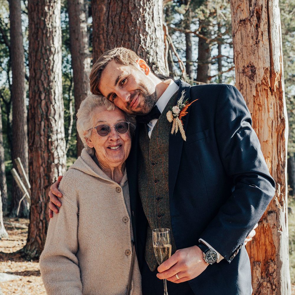 Groom hugs wedding guest in woodland wedding