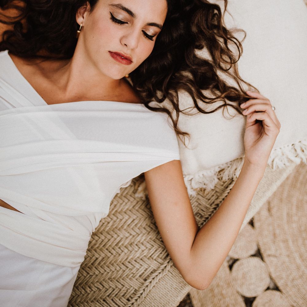 Bride lays outdoors with dark crimped hair 