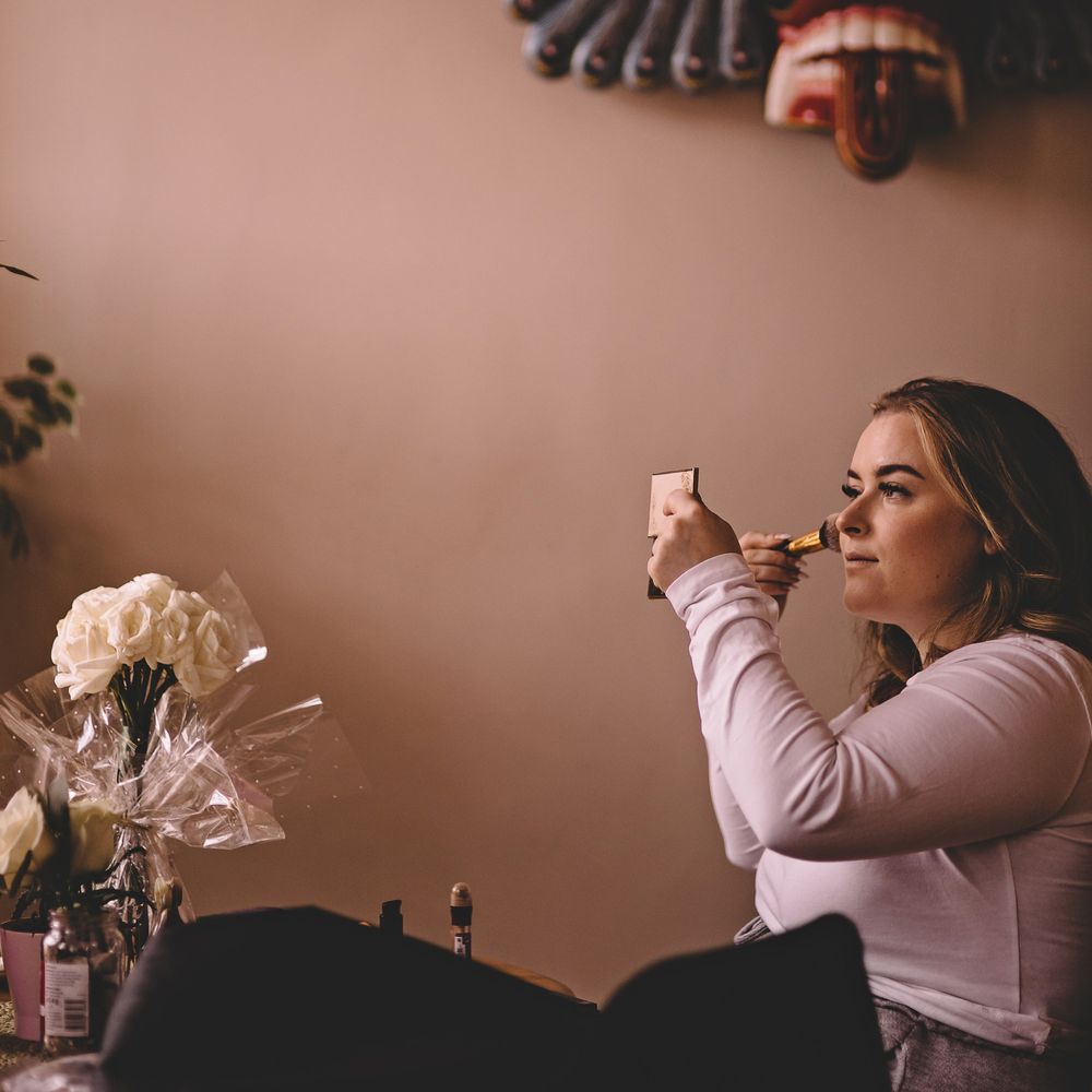 Bride applies her own blusher on the morning of her wedding