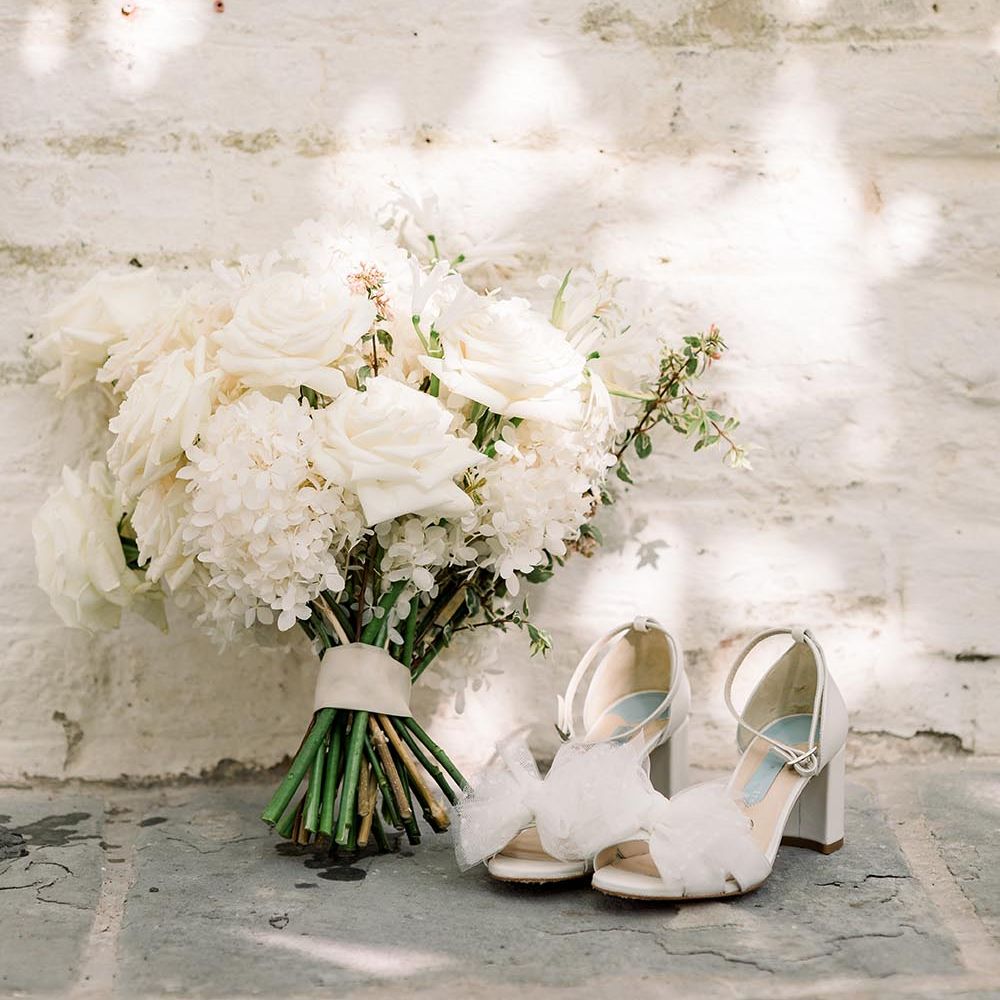 all white rose and hydrangea wedding bouquet and Charlotte Mills bow wedding shoes 