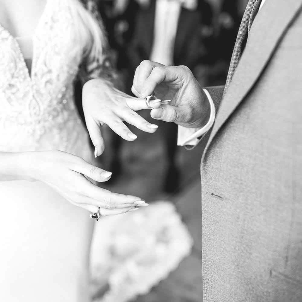 Black & white image of groom giving bride ring on wedding day