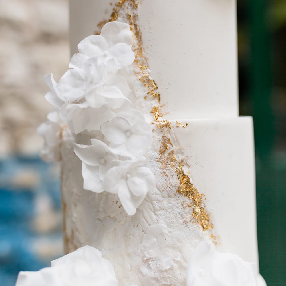 White buttercream wedding cake with gold geode detail and floral decor 