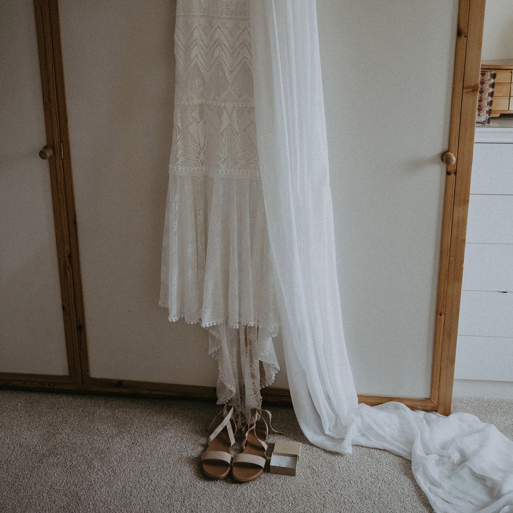 Grace Loves Lace Bardot wedding dress on hanger with veil and sandals before Isle of Wight wedding with macrame wedding decor