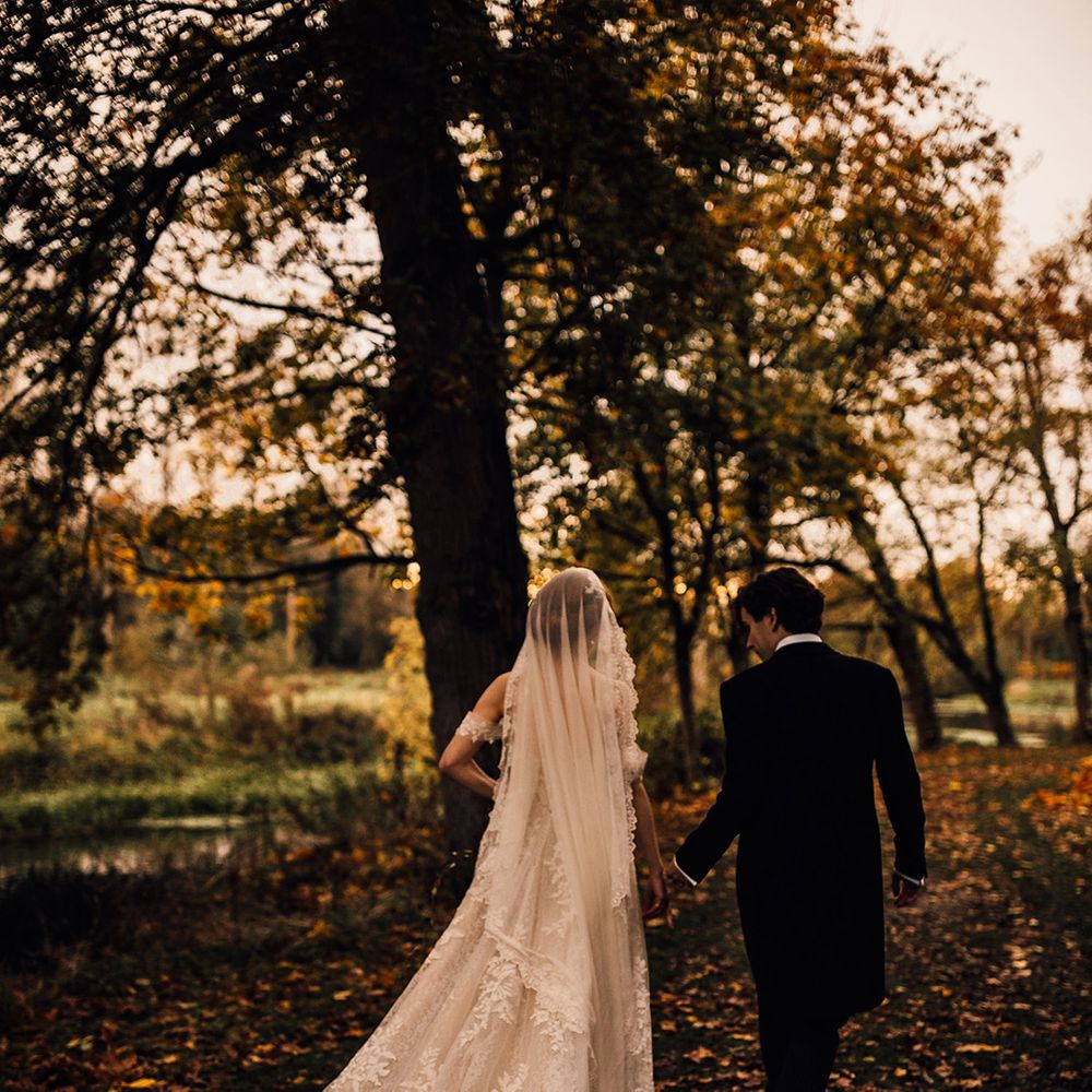Lace detail dress for bride as she walks through Oxnead Hall grounds with groom