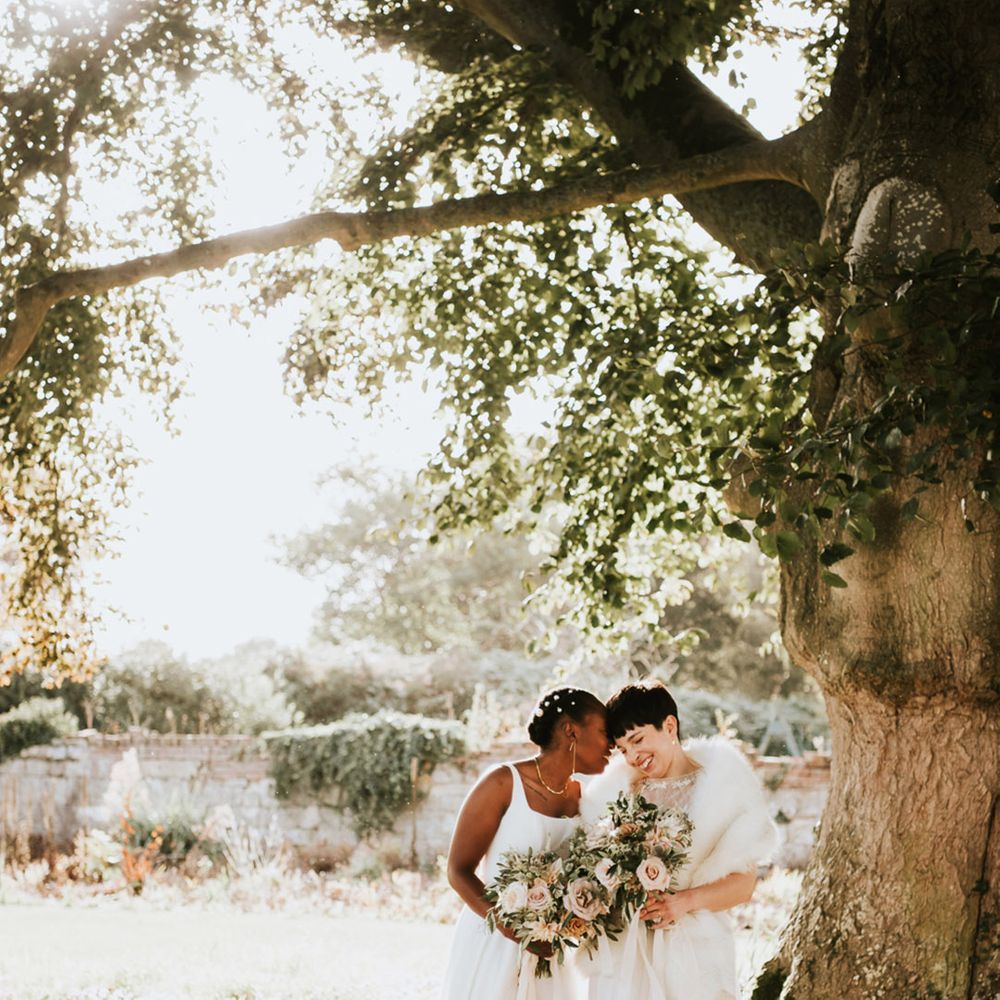 Romantic wedding photograph under a tree of two brides at their LGBTQI+ Elmore Court wedding 