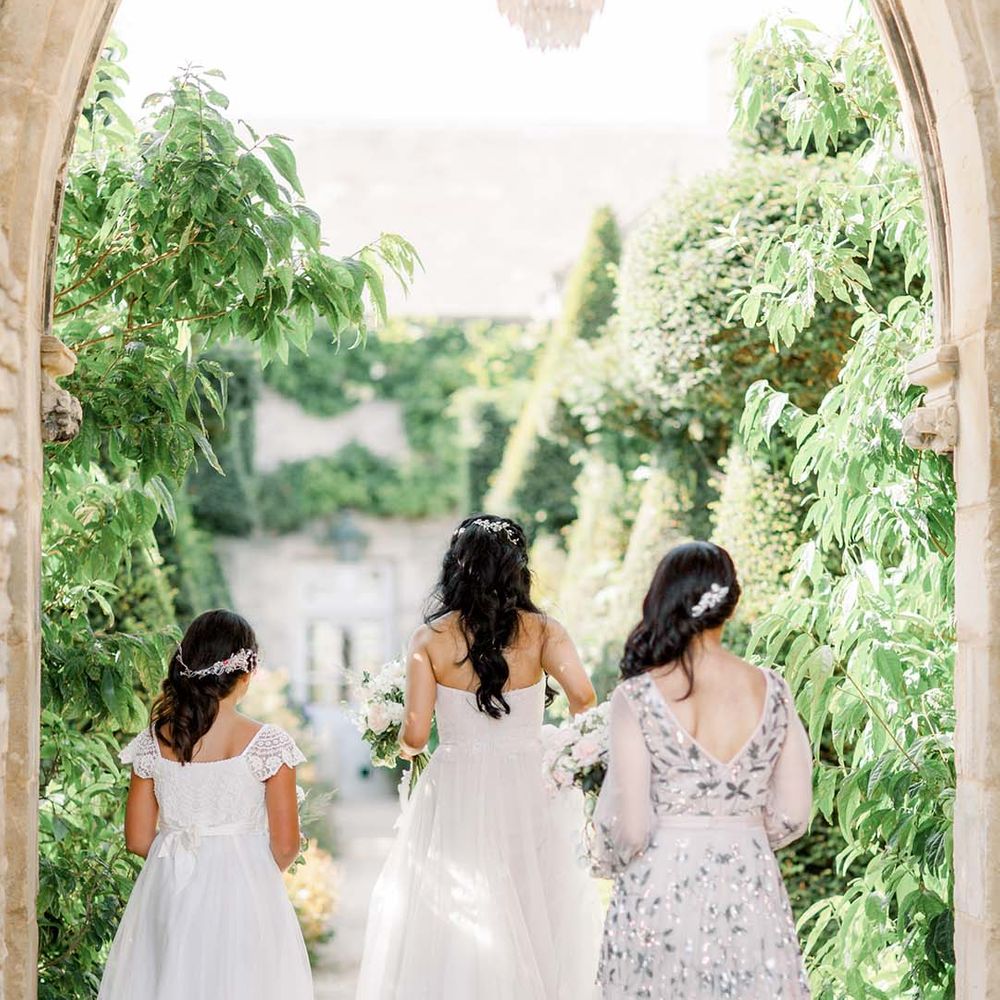Bride walks with flower girl and bridesmaid wearing embellished gown 
