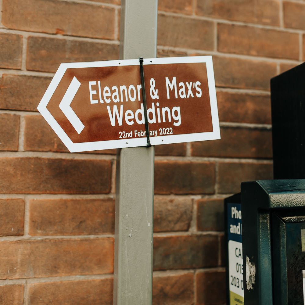 Brown wedding road sign reading 'Eleanor and Max's Wedding 22 February 2022'