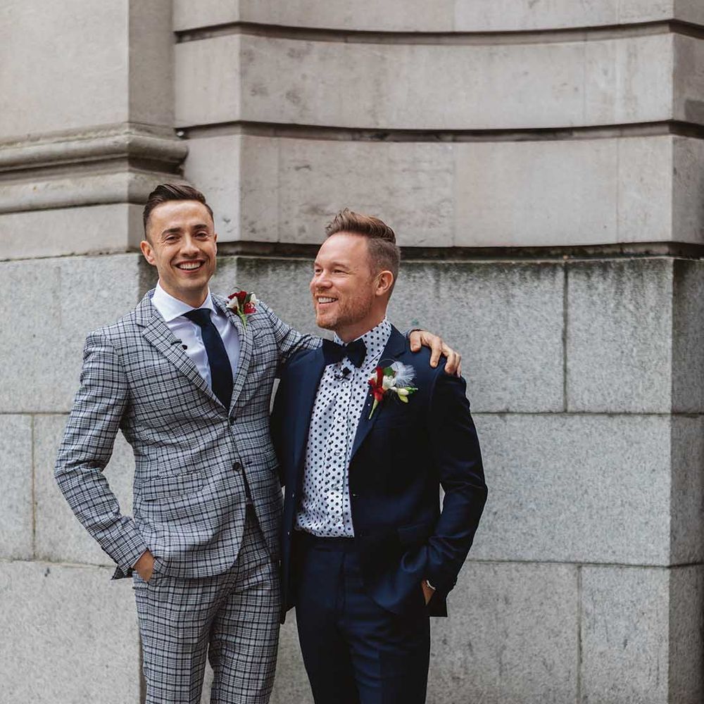Grooms stand with one another wearing gay wedding suits for Chelsea Old Town Hall wedding