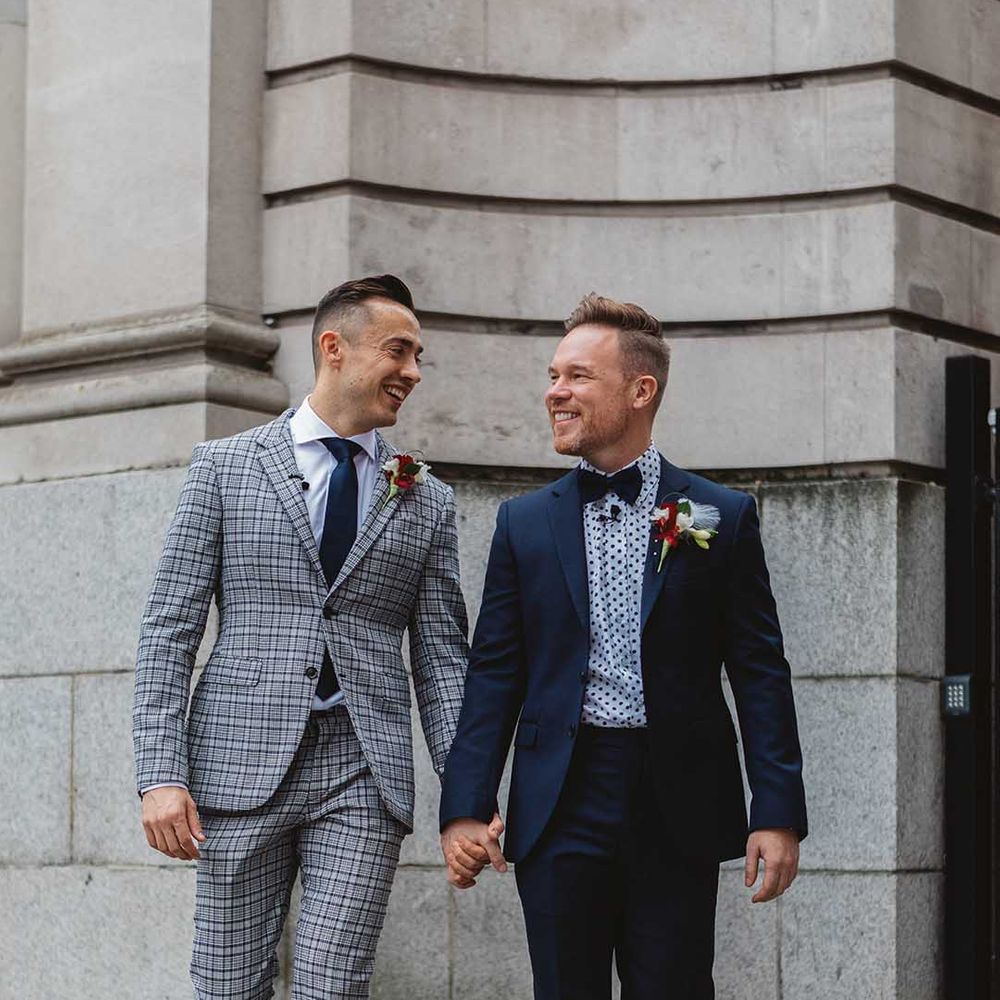 Grooms walk with one another on their wedding day outdoors 