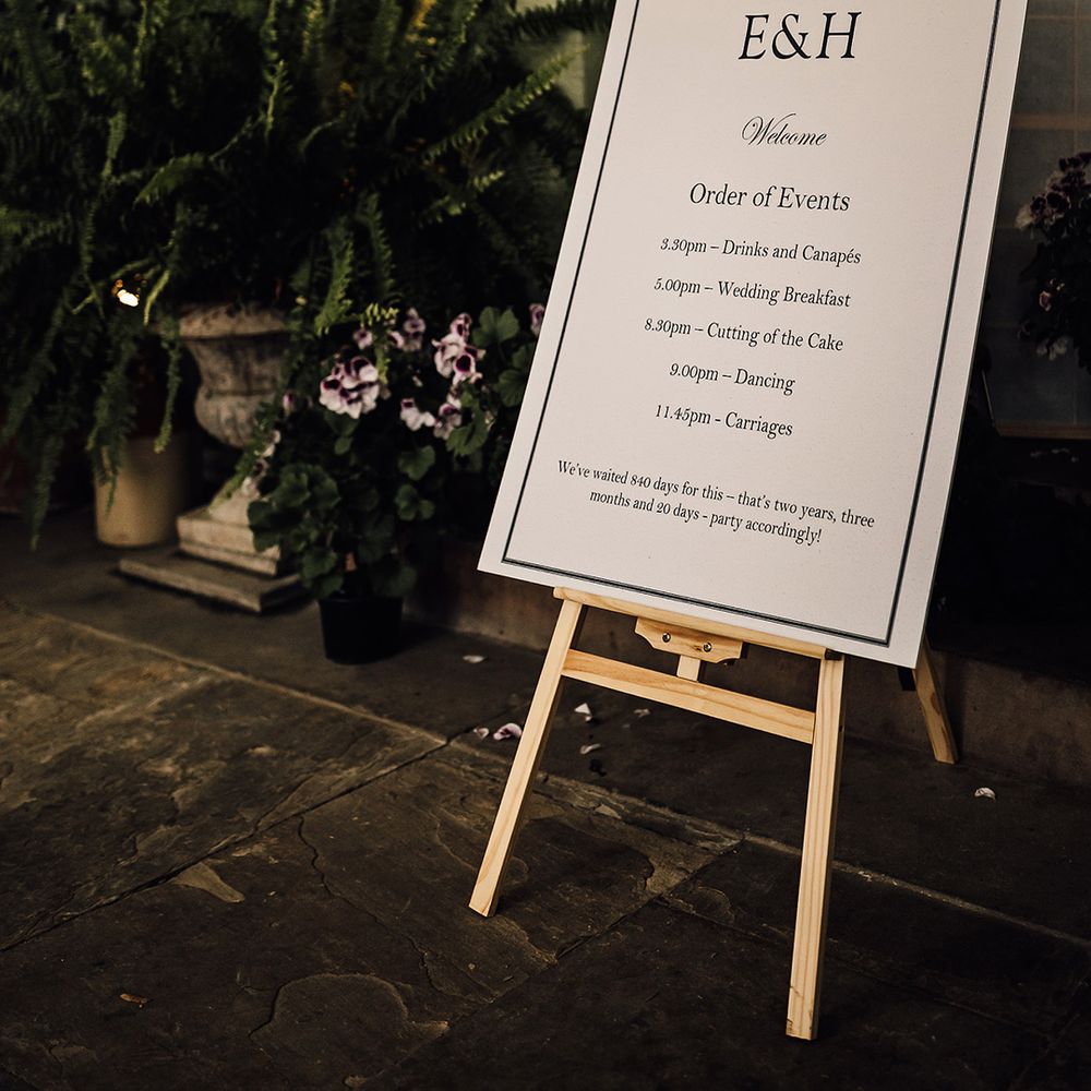 Classic black and white wedding welcome and order of the day sign on wooden easel for traditional wedding 