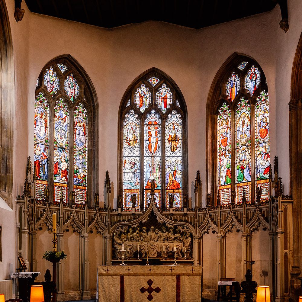 Grand church wedding venue with stained glass windows and elaborate gold religious paraphernalia  