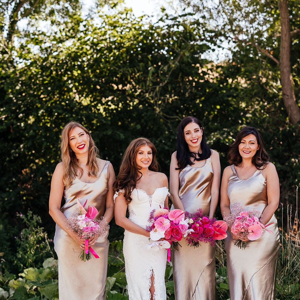 Bridesmaids wear satin champagne bridesmaid dresses and stand with bride who wears lace wedding dress 