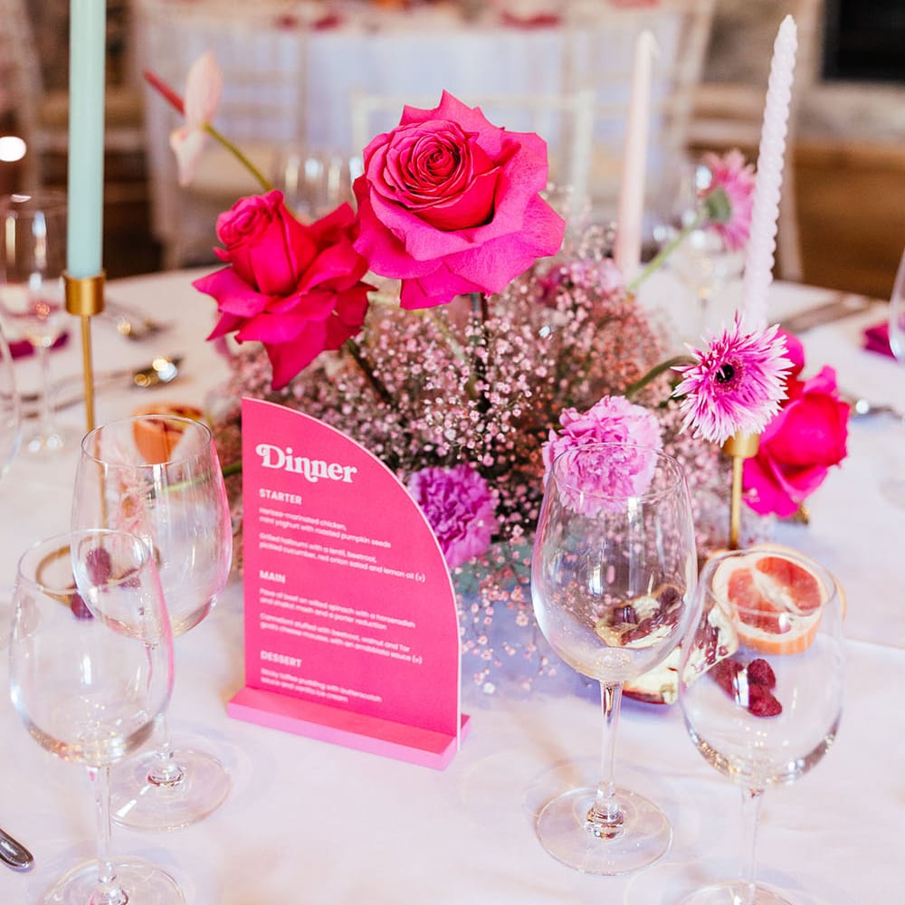 Bright pink floral centrepiece for modern tablescape surrounded by pastel candles 